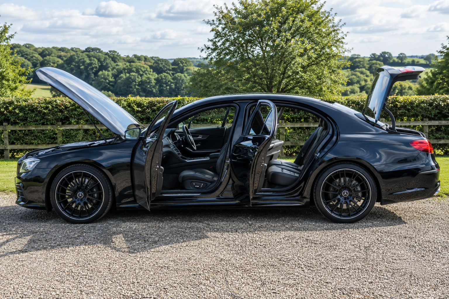 Full car detailing service on black luxury sedan with doors, bonnet and boot open outdoors